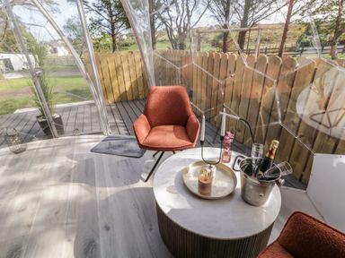 A transparent dome room with two orange chairs a round table with champagne and glasses at Number 2 Dome in Derrybeg County Donegal