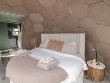 A bedroom with a bed towels and a nightstand with a lamp at Number 2 Dome in Derrybeg County Donegal