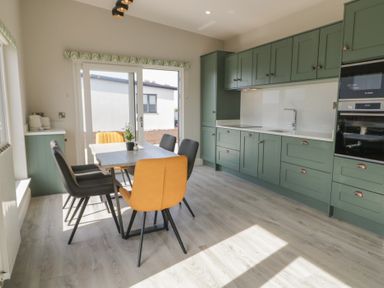 A kitchen with green cabinets and a dining table with yellow and black chairs at Number 2 Villa - The View in Derrybeg County Donegal