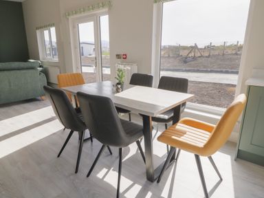 A dining area with six chairs around a rectangular table near large windows at Number 2 Villa - The View in Derrybeg County Donegal
