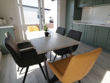 A dining area with a wooden table surrounded by six chairs in a kitchen at Number 2 Villa - The View in Derrybeg County Donegal