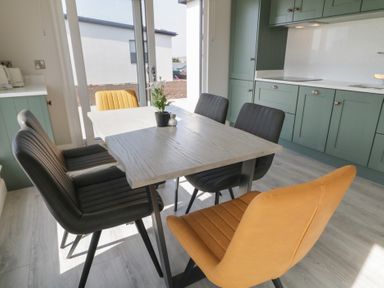 A dining table with six chairs and a plant in a kitchen with green cabinets at Number 2 Villa - The View in Derrybeg County Donegal