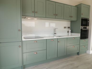 A kitchen with green cabinets a white countertop a sink and built in oven at Number 2 Villa - The View in Derrybeg County Donegal