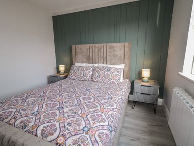 A bedroom with a bed and patterned bedding flanked by two nightstands with lamps at Number 2 Villa - The View in Derrybeg County Donegal