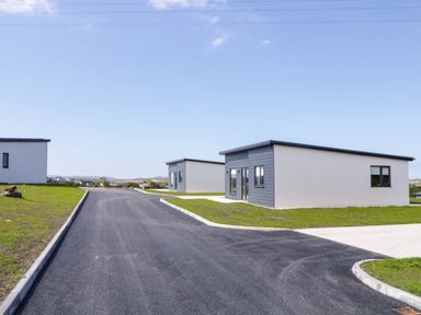 A paved road with modern single-story houses on grassy plots at Number 2 Villa - The View in Derrybeg County Donegal