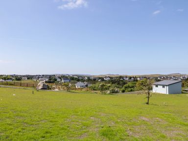 A grassy field with a shed fence and houses in the background at Number 2 Villa - The View in Derrybeg County Donegal