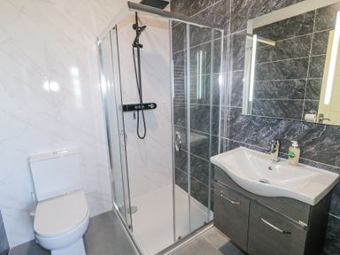 A bathroom with a toilet a glass enclosed shower and a sink with a mirror at Number 5 Villa - The View in Derrybeg County Donegal