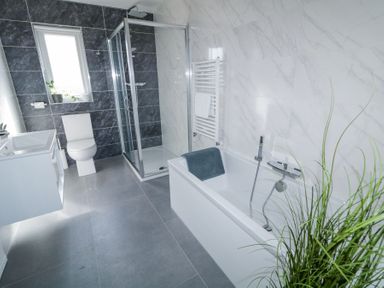 A bathroom with a bathtub a shower a toilet a sink and plants at Number 5 Villa - The View in Derrybeg County Donegal