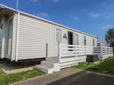 A mobile home with white siding and a small porch with steps on a grassy lot at HW42 in Bognor Regis