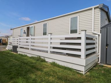 A mobile home with white railings and outdoor seating on a wooden deck at HW42 in Bognor Regis