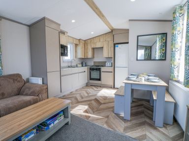 A kitchen and dining area with a sofa dining table with dishes and board games on a coffee table at HW42 in Bognor Regis