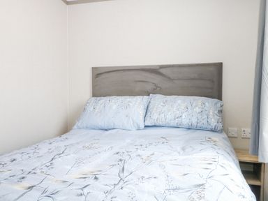 A bed with blue floral bedding and a grey headboard in a bedroom at HW42 in Bognor Regis