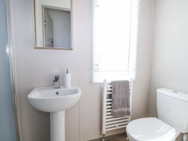 A bathroom with a sink pedestal mirror towel radiator and toilet at HW42 in Bognor Regis
