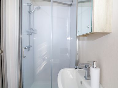 A bathroom with a shower enclosure a sink with a faucet and a soap dispenser at HW42 in Bognor Regis