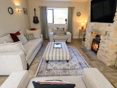 A living room with furniture and a fireplace at Yew Tree Cottage in Mealsgate near Ireby