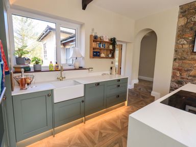 A kitchen with cabinets and a large sink at Yew Tree Cottage Mealsgate near Ireby