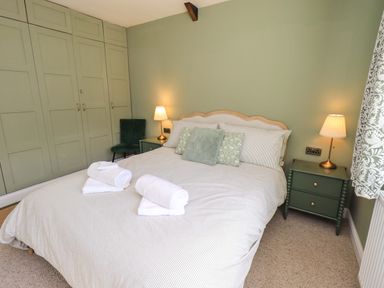 A bedroom with a bed and a wardrobe at Yew Tree Cottage Mealsgate near Ireby