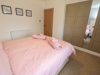 A bedroom with a bed and towels at Yew Tree Cottage Mealsgate near Ireby