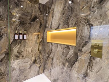 A shower with bottles and gold accents at Yew Tree Cottage Mealsgate near Ireby