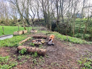 A garden area with a fire pit and garden beds at Yew Tree Cottage Mealsgate near Ireby