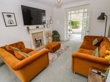A living room with orange sofas and a television at Burry House Llanmorlais