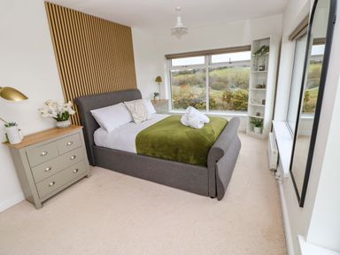 A bedroom with a bed, nightstand, and large window at Burry House in Llanmorlais