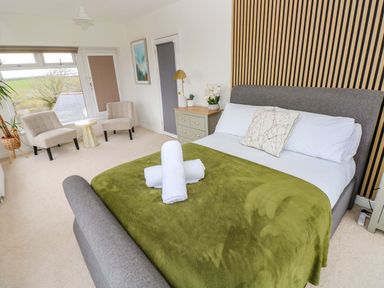 A bedroom with a bed and two chairs at Burry House Llanmorlais