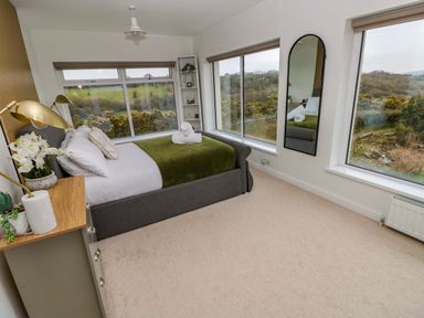 A bedroom with a bed and large windows at Burry House Llanmorlais