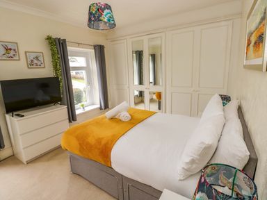 A bedroom with a bed and television at Burry House Llanmorlais