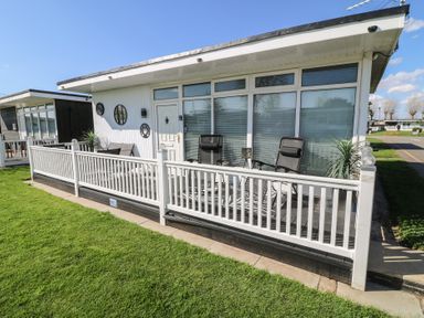 A front porch with chairs and decorative plants at 56 Cherry Park Chalet in Chapel St Leonards
