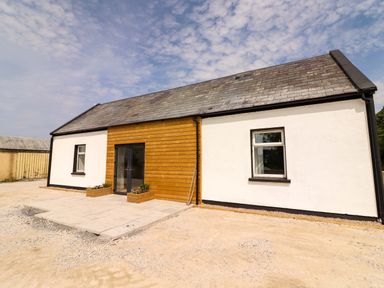 A house exterior with a wooden front door and planters at Teach Ti in Miltown Malbay