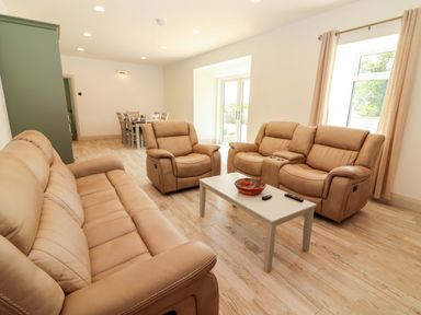 A living room with beige furniture and a table at Teach Ti in Miltown Malbay