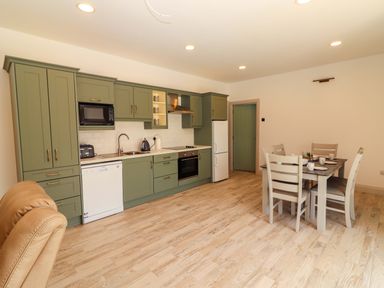 A kitchen with cabinets and dining table at Teach Ti in Miltown Malbay