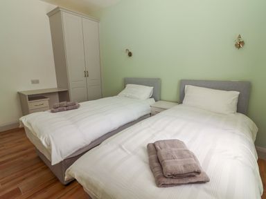 A bedroom with two beds and a wardrobe at Teach Ti in Miltown Malbay