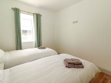 A bedroom with two beds and towels at Teach Ti in Miltown Malbay