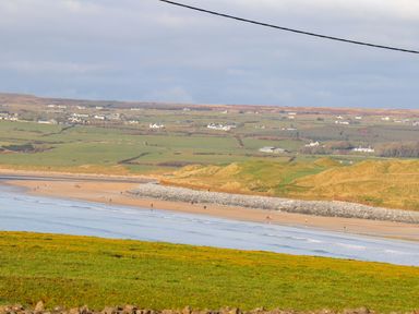 A beach scene with people and hills in the distance at Teach Ti in Miltown Malbay