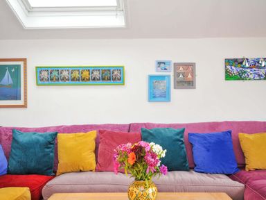 A living room with colorful cushions on a sofa and framed artwork on the wall at 5 Esplanade in Fowey