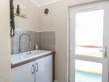 A laundry room with a sink and cabinet at Life's a Beach in Bacton