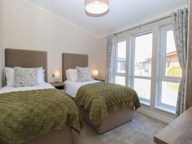 A bedroom with twin beds and windows at Life's a Beach in Bacton