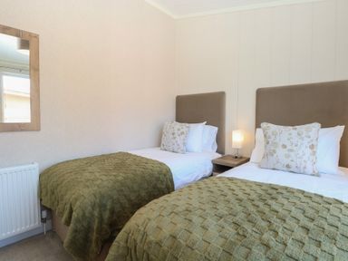 A bedroom with two beds and a mirror at Life's a Beach in Bacton
