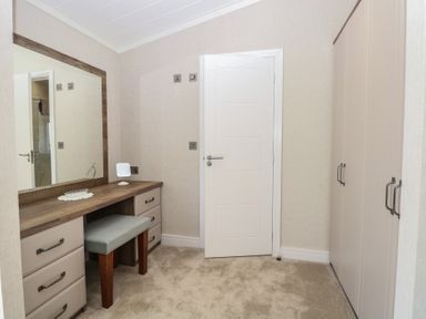 A dressing room with a mirror and a wardrobe at Life's a Beach in Bacton