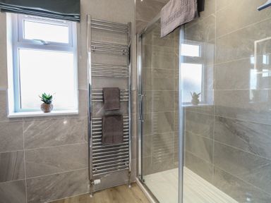 A bathroom with a shower and towel rail at Life's a Beach in Bacton