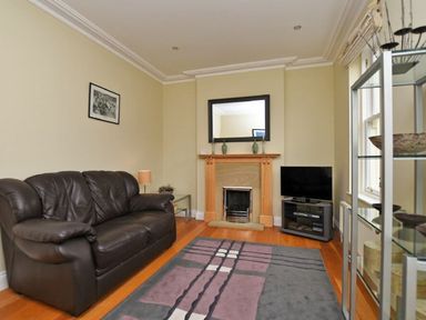 A living room with a leather sofa fireplace and television at Churchside in Alnwick
