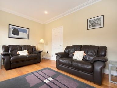 A living room with two brown leather sofas a lamp and framed pictures on the wall at Churchside in Alnwick