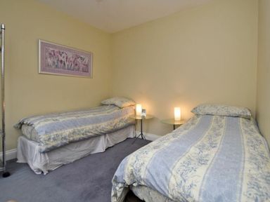 A bedroom with two single beds and side tables with lamps at Churchside in Alnwick