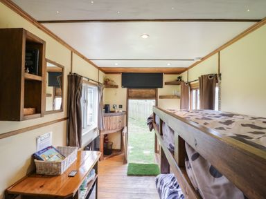 A narrow bedroom with bunk beds table and shelves at Buttercup Cow Shed 3 Easton near Campsea Ashe