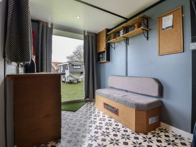 A small room with a bench seat cushions shelves with plants and a corkboard at Dozy Dotty Cow Shed 4 Easton near Campsea Ashe
