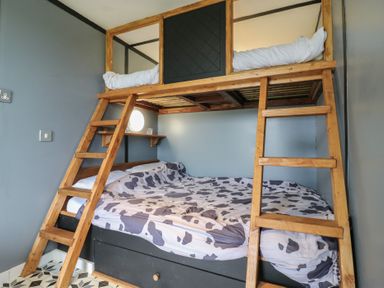 A bedroom with a wooden bunk bed and cow print bedding at Dozy Dotty Cow Shed 4 Easton near Campsea Ashe