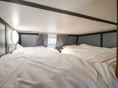 A bedroom with two beds covered with white blankets and a window with patterned curtains at Dozy Dotty Cow Shed 4 in Easton near Campsea Ashe