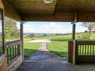 View from a wooden porch overlooking grassy fields and hills at Pen Y Clawdd Beggar's Bush near Presteigne